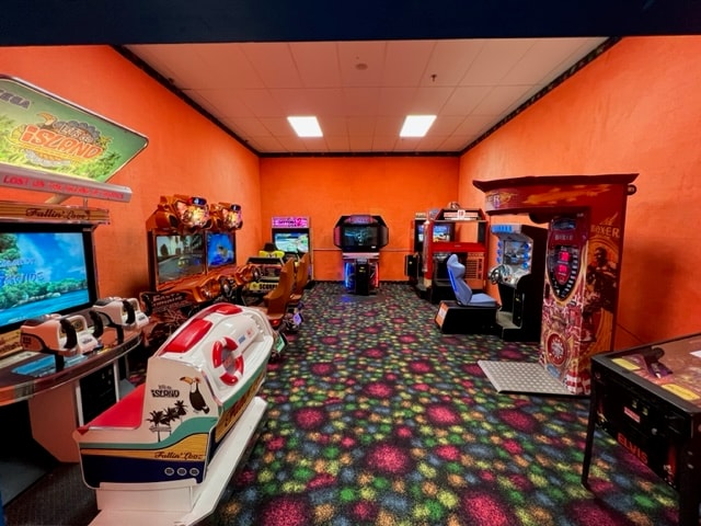 Arcade game room with orange walls and racing games at Newport Entertainment Center